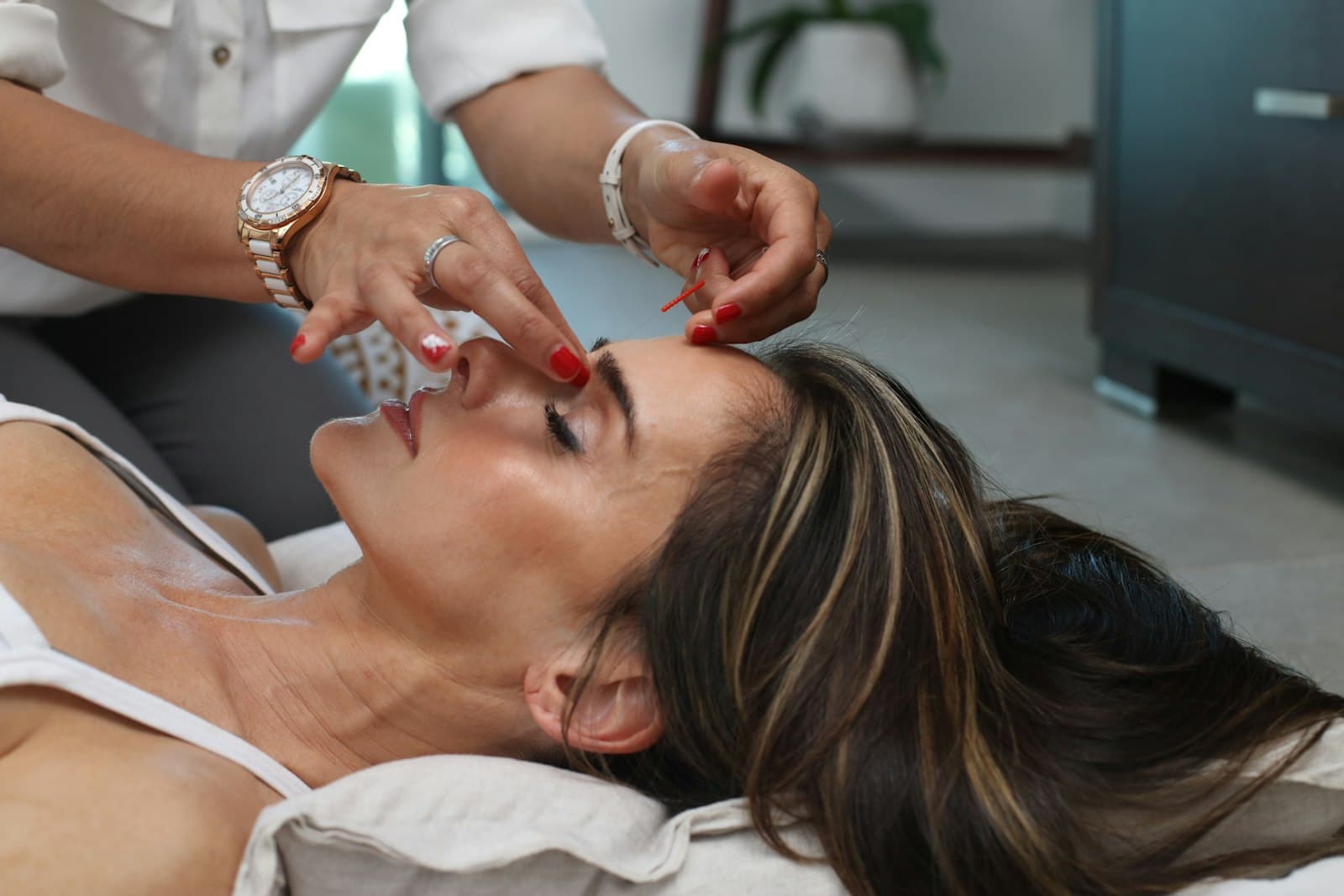 Estetista esegue un massaggio viso a una cliente distesa, luce calda